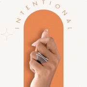Hand holding a pen with 'Intentional' text on an orange arch against a white background