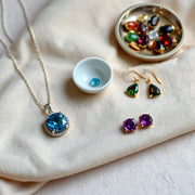 Necklace, bracelet, and earrings featuring colorful gemstones arranged on a neutral fabric