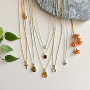 Delicate layered necklaces with different chain lengths and small minimalist pendants arranged neatly