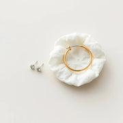 Small stud and hoop earrings displayed on a neutral background for sensitive-skin comfort