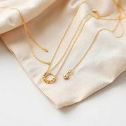 Delicate lightweight gold necklaces with fine chains and small pendants arranged on neutral fabric