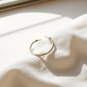 Classic hoop earrings displayed on light fabric under soft natural light