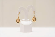 a pair of gold and diamond earrings on a white stand