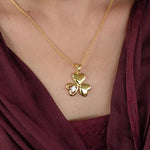 Load image into Gallery viewer, Gold necklace with a clover-shaped pendant worn by a person in a burgundy top.