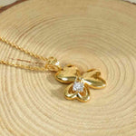Load image into Gallery viewer, Gold necklace with a butterfly pendant on a wooden surface