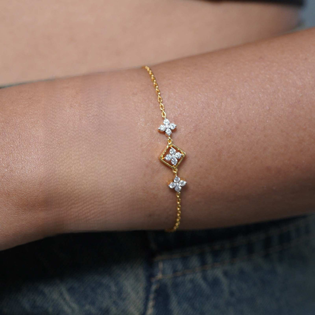 Gold bracelet with diamond-like stones on a wrist against a blurred background