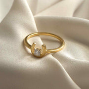 Gold ring with a diamond on a beige fabric background From Silvilus 