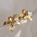 Load image into Gallery viewer, Gold earrings with diamond-like stones on a clear stand against a neutral background