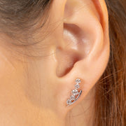 Close-up of an ear wearing a silver earring with small stones.