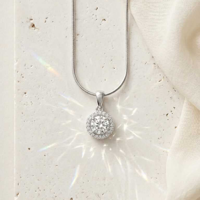 Silver necklace with a round pendant on a white stone surface
