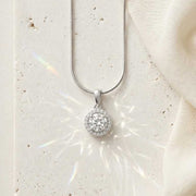 Silver necklace with a round pendant on a white stone surface