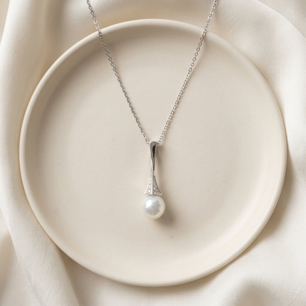 Pearl necklace on a white plate with a soft beige background