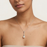 Load image into Gallery viewer, Woman wearing a silver necklace with a pearl pendant on a plain background