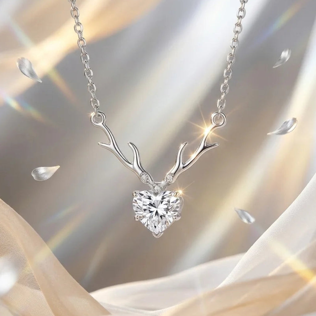 Silver necklace with deer antler design and heart-shaped gemstone on a soft fabric background