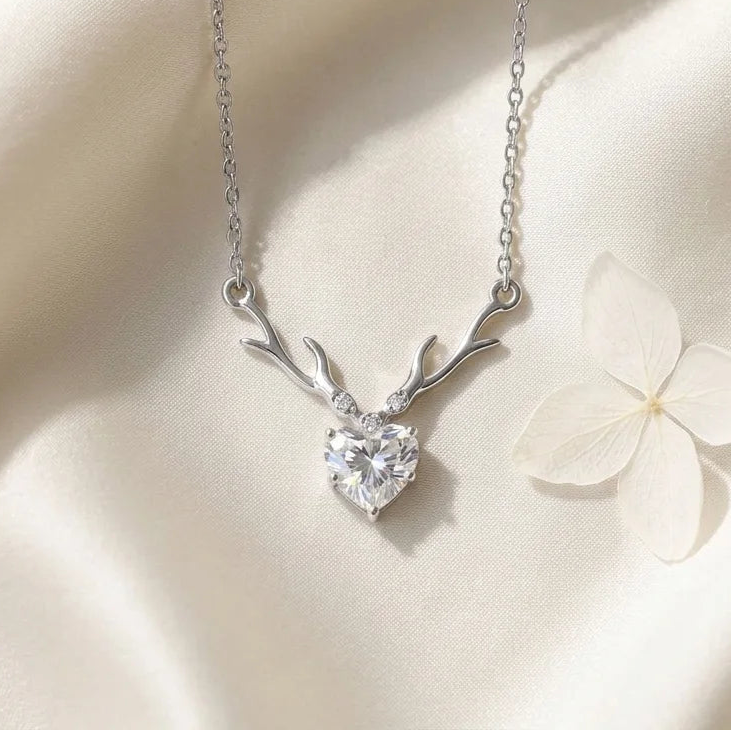 Silver necklace with heart-shaped pendant on a soft beige background