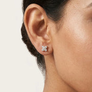 Close-up of a woman wearing a diamond earring on a neutral background