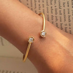 Load image into Gallery viewer, Gold bracelet with diamond accents on a wrist against a blurred book background